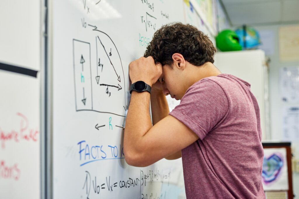 Stressed teenager student leaning on whiteboard